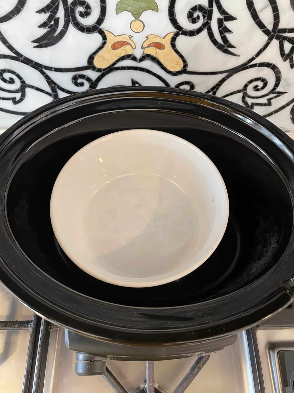 A small oven proof bowl inside a large crock pot bowl