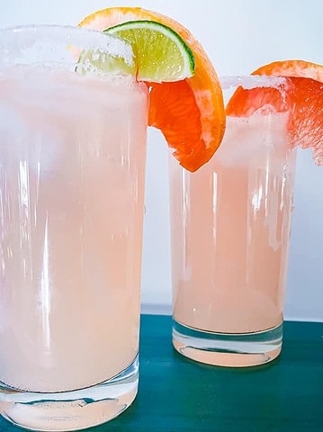 2 tall Collins glasses filled with ice, grapefruit soda, grapfruit and lime juice garnished with grapefruit and lime slices