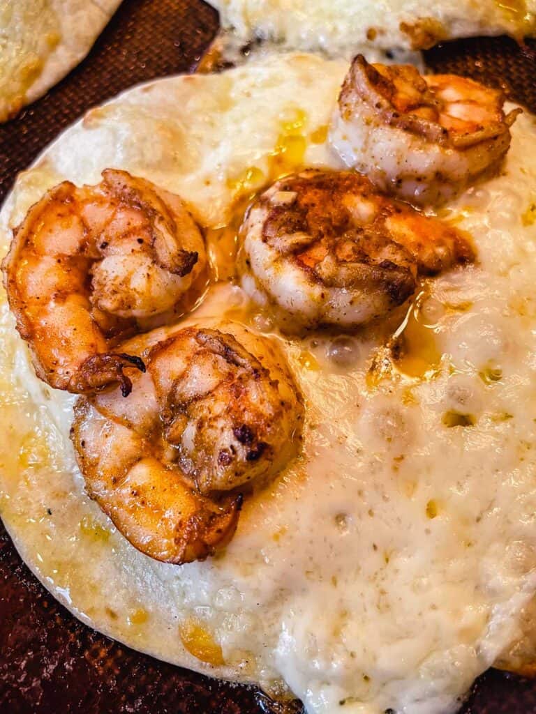 out of the oven melted cheese and spicy shrimp on a white corn tortilla
