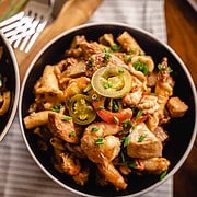 2 bowls filled with smoked sausage, chicken, peppers , penne pasta in a spicy cajun Alfredo sauce sitting on a table with two forks