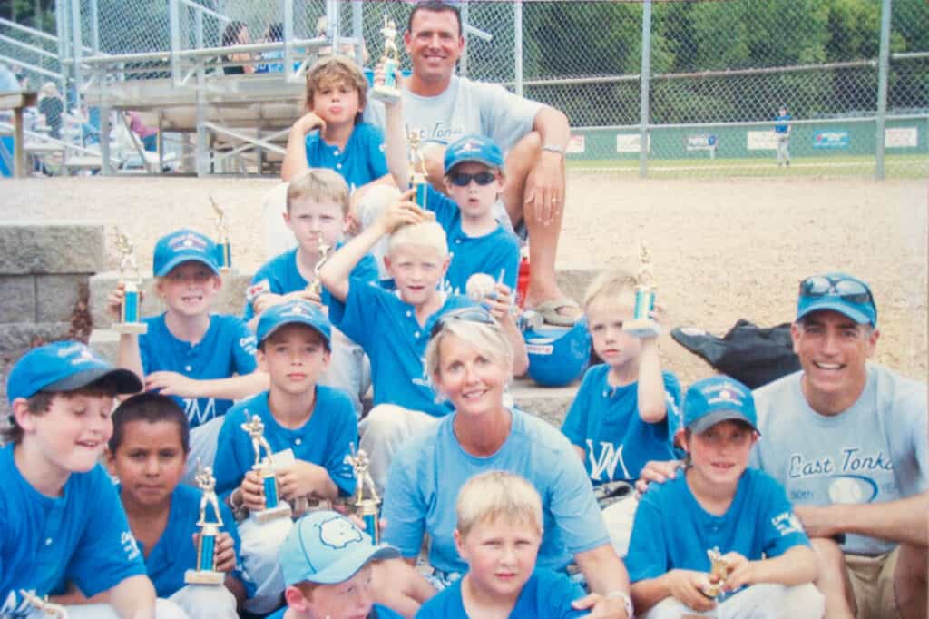 8 year old boys in royal blue team t-shirts holding their little league trophies with the 3 coaches