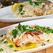 Baked Halibut on a bed of mushroom ravioli and a creamy alfredo sauce with green peas