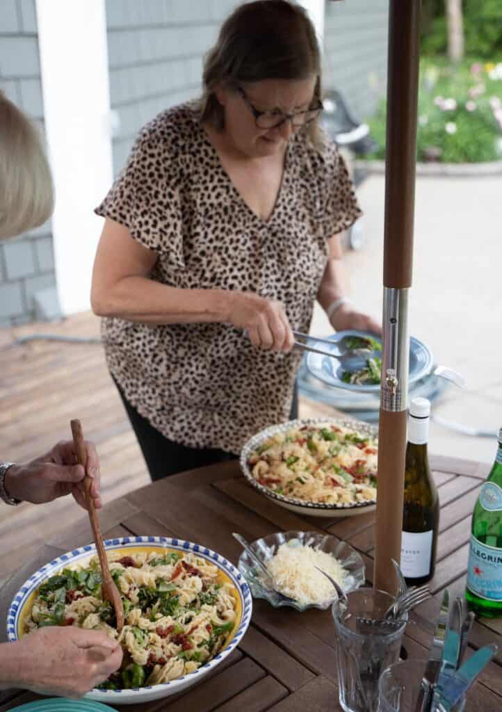 Mary dishing into a serving bowl of Orecchiette Pasta with broccolini and sun-dried tomatoes