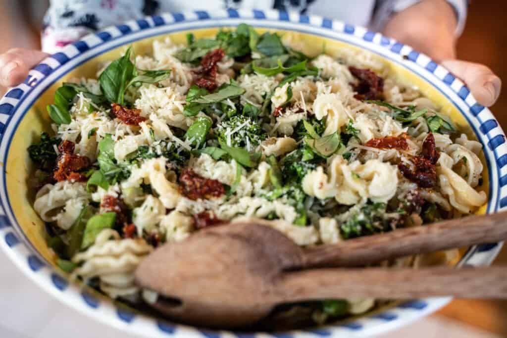 Serving Bowl of Orecchiette Pasta with Broccolini, Sun-dried Tomatoes and garnished with basil and parmesean