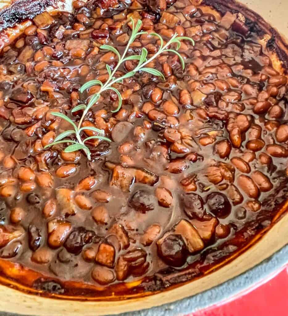 BBQ Baked Beans after being baked with a sprig of rosemary