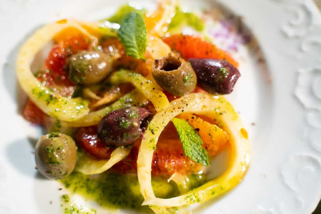 Fennel, Olives, orange segments tossed with a mint dressing on a plate.