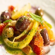 Fennel, orange segments, olives tossed in a mint vinaigrette on a white plate