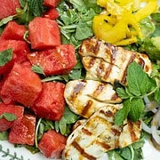 Watermelon and grilled halloumi, pickled fennel, avacado, mint, red onion on a white plate with a balsamic dressing