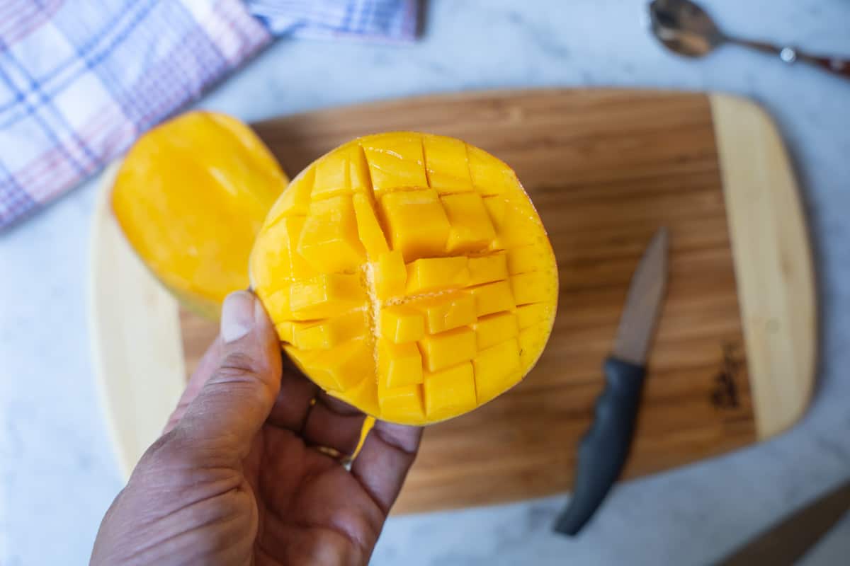 Mango halve held in hand showing cross-hatch pattern