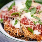 Eggplant parmesan for two in a white casserole dish garnished with basil