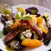 Roasted beet salad for two garnished with orange segments, picled fennel and a mint vinegar dressing on a white plate