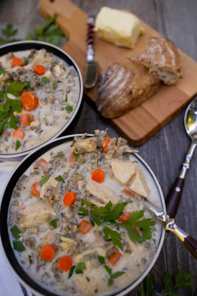 Leftover Turkey Wild Rice Soup in a bowl alongside bread on a cutting board