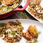 Easy one-pot chicken orzo recipe for two in a red dutch oven and on 2 white serving plates with dill, feta, artichokes and olives