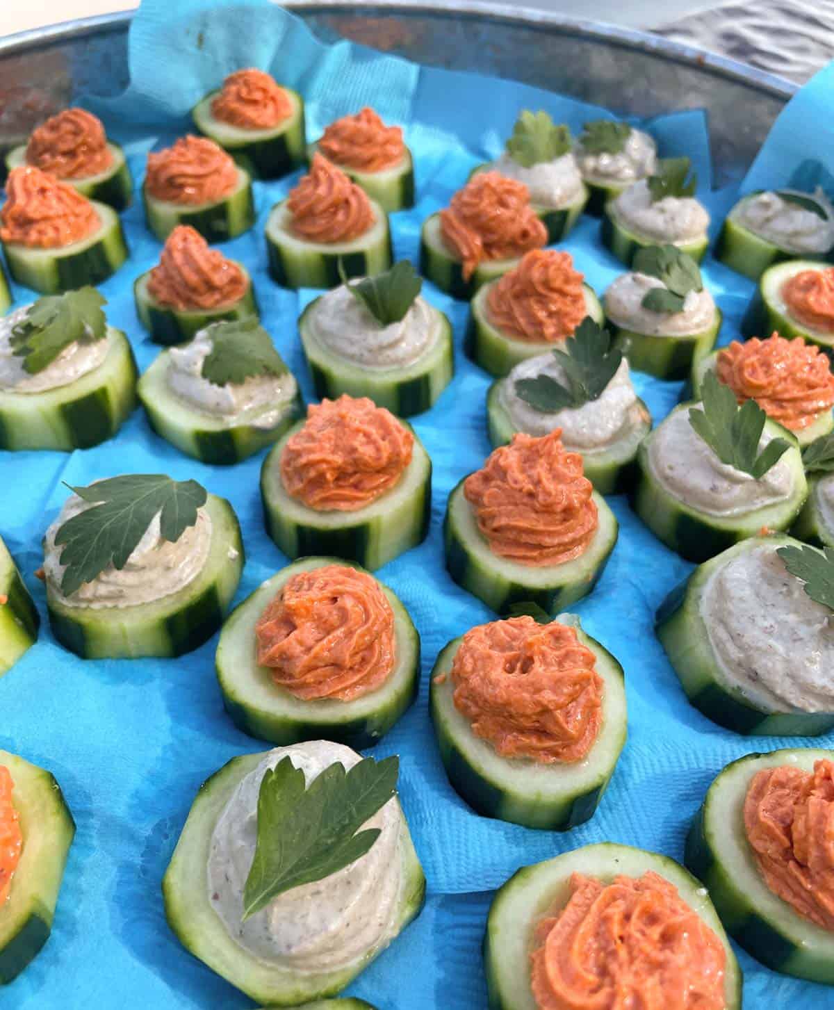 cucumber canapes two ways, sun-dried tomato mousse and smoked salmon on a blue tray