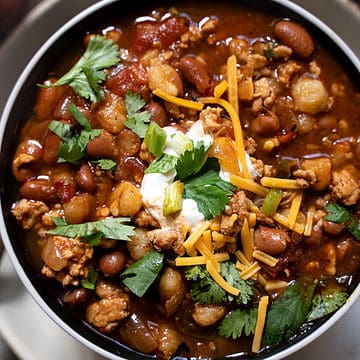 Turkey Chili for two in a bowl garnished with cilantro, cheddar cheese and sour cream