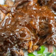 A Jewish Passover Brisket cooked in the oven on a white platter garnished with parsley