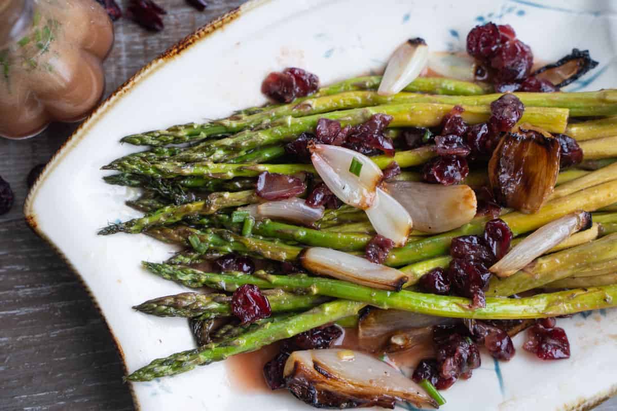 Asparagus For Two with roasted shallots and cranberry vinaigrette on a white serving platter