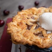 Cherry pie for two in a 6 inch pie plate with a scoop of vanilla ice cream on top