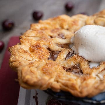 Cherry pie for two in a 6 inch pie plate with a scoop of vanilla ice cream on top
