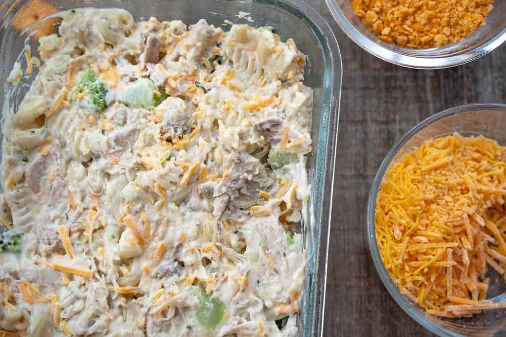 Chicken Broccoli Pasta Casserole in a glass baking dish with Toppings in bowls on a table