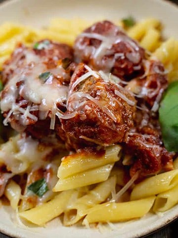 Sicilian Meatballs for Two on a bed of pasta served on a tan plate