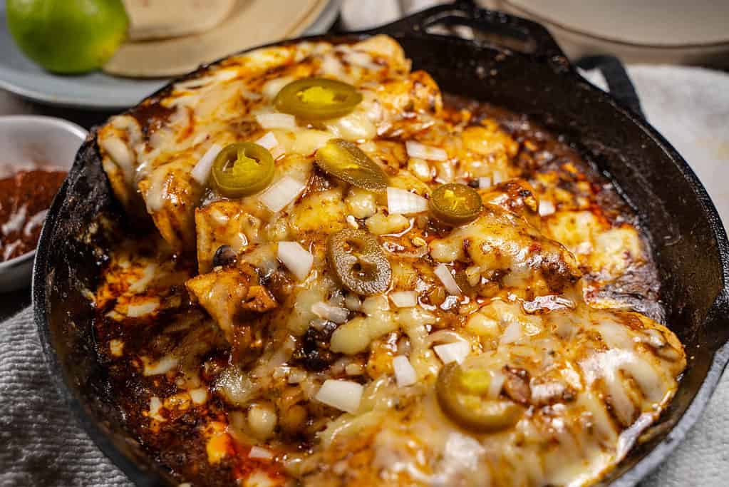 Tex-Mex Cheese Enchiladas For two in a 10-inch cast iron skillet garnished with jalapenos and onion