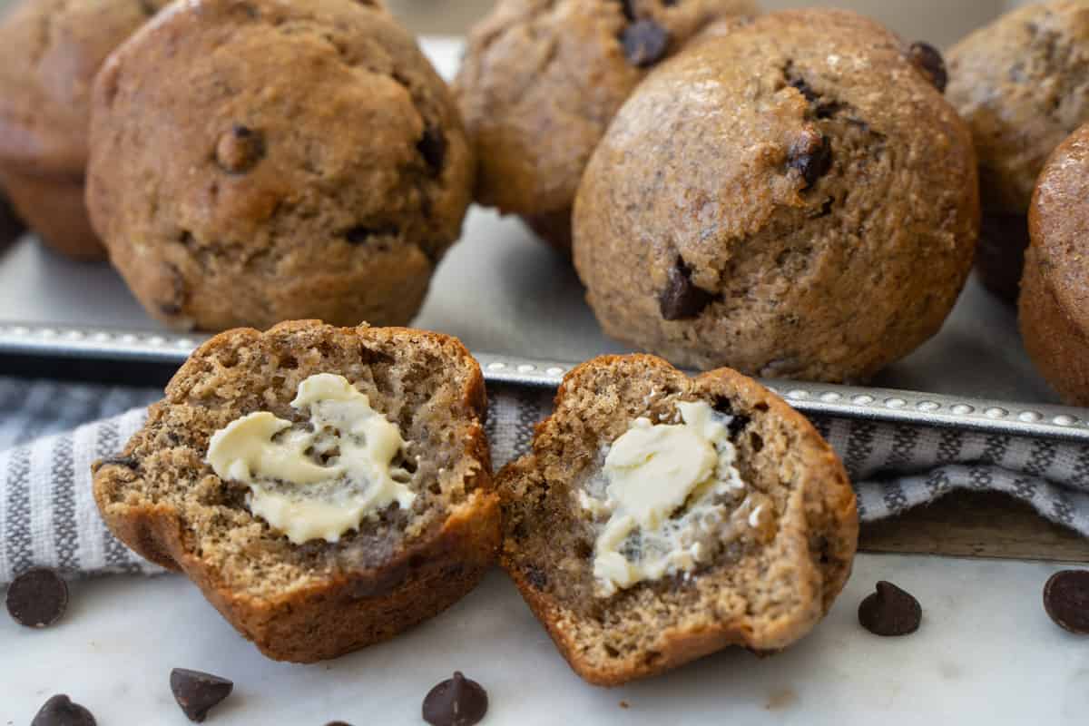 Banana bread with applesauce baked as muffins cut open slathered with butter