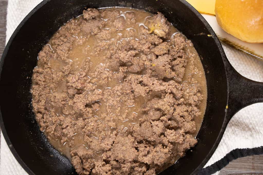 ground beef simmering in a cast iron skillet