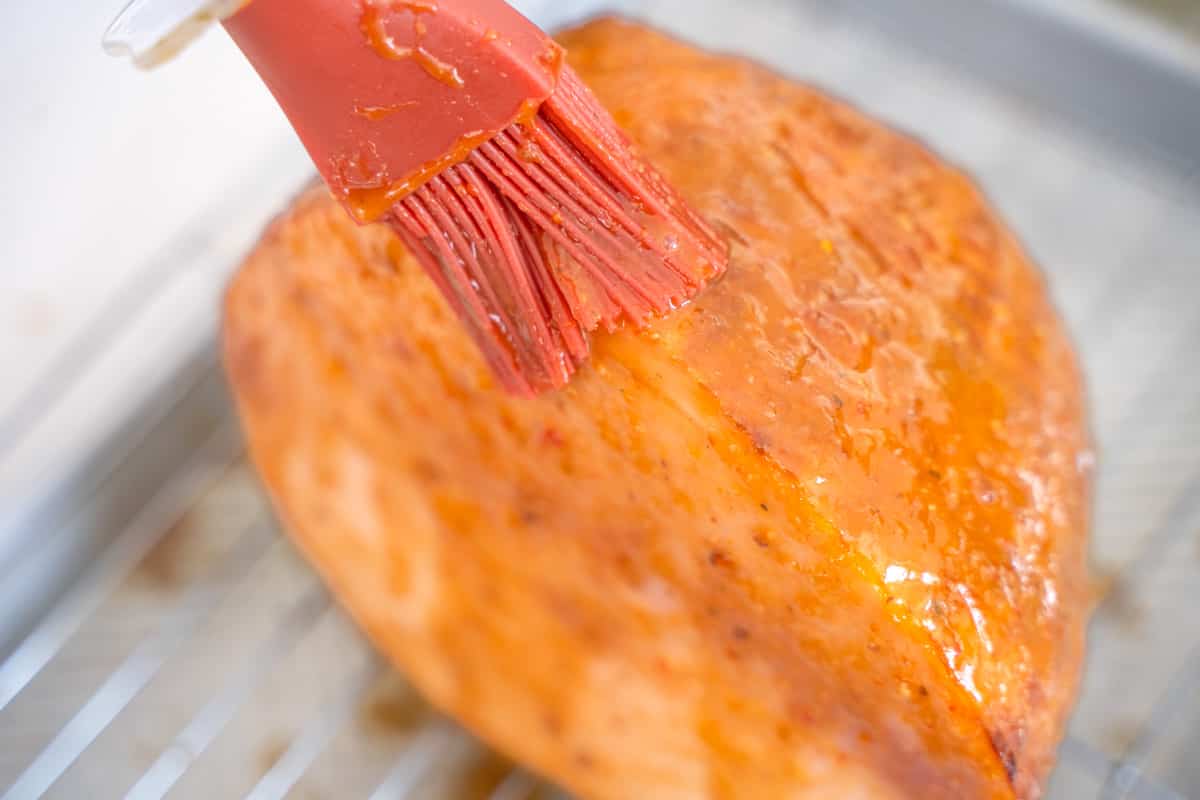mango chutney glaze being brushed on to a small baked ham