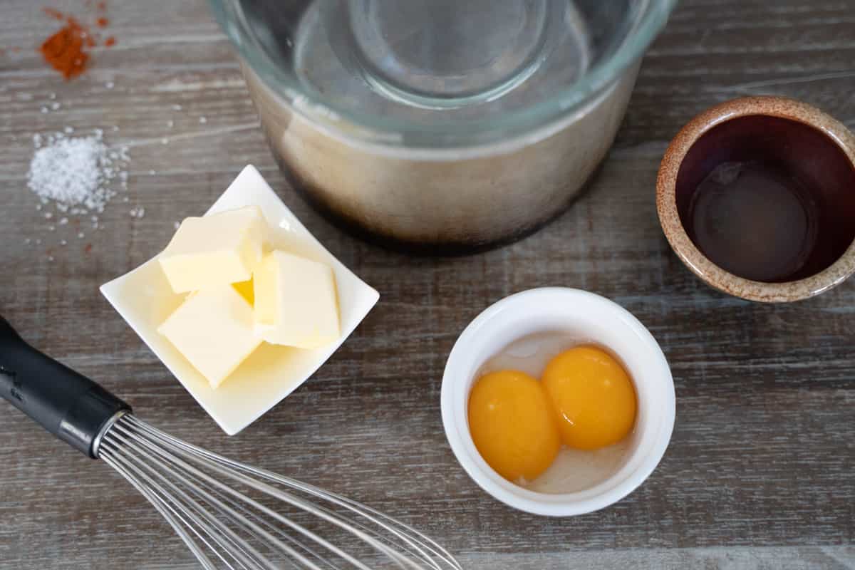 foolproof hollandaise sauce ingredients set on a wooden table