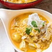 Fish stew ladled into bowl garnished with whip cream and pea sprouts