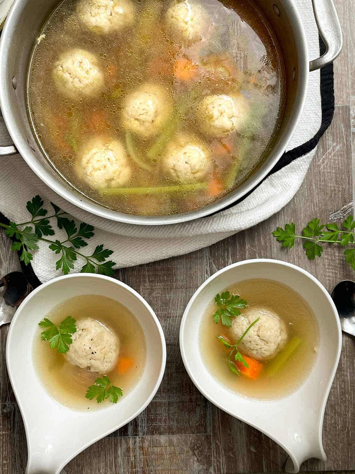 matzo balls in chicken stock in stock pot and ladled into 2 soup bowls