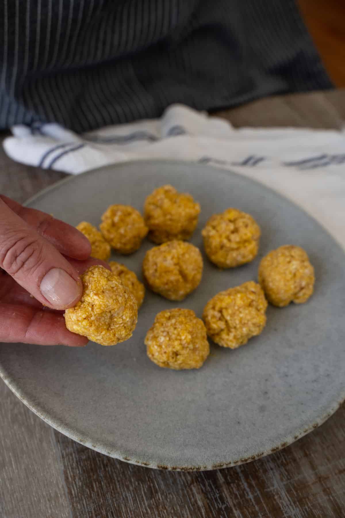 9 matzo balls on a plate with one being held between fingers