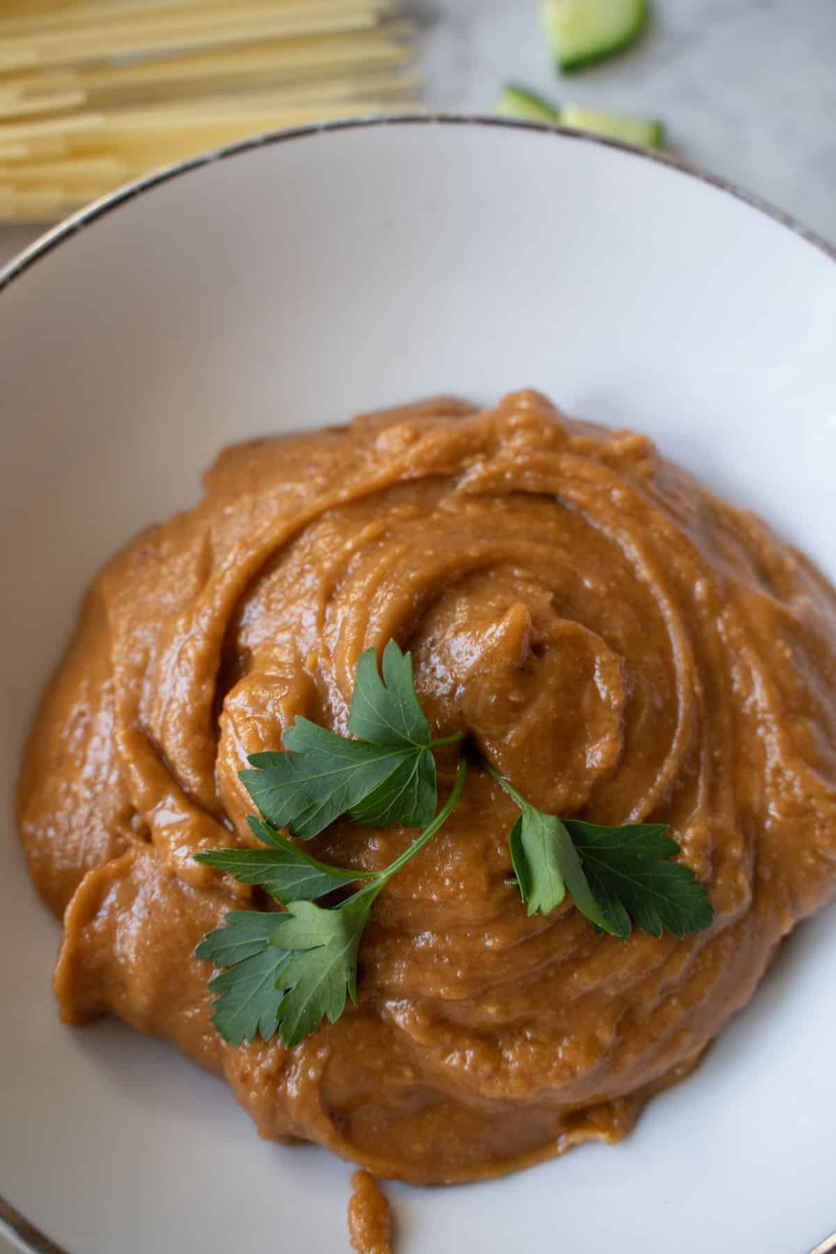 peanut sauce in a white bowl garnished with parsley