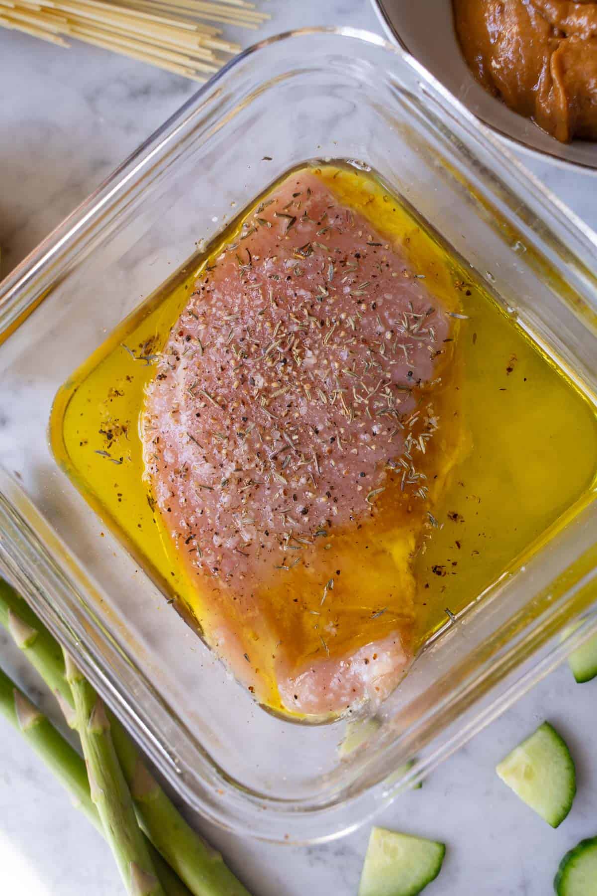 chicken breast marinating in a lemon and olive oil with thyme marinade