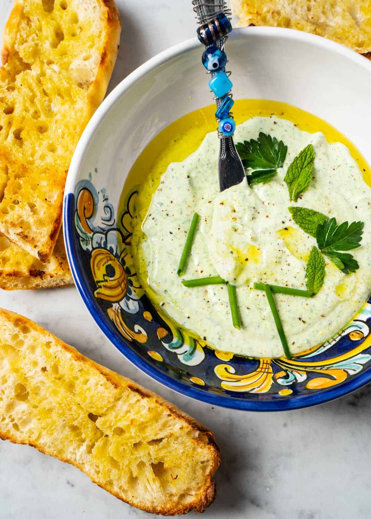 Ricotta appetizer in serving bowl surrounded by grilled baguette slices