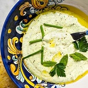 ricotta appetizer in a serving bowl surrounded by slices of grilled baquette