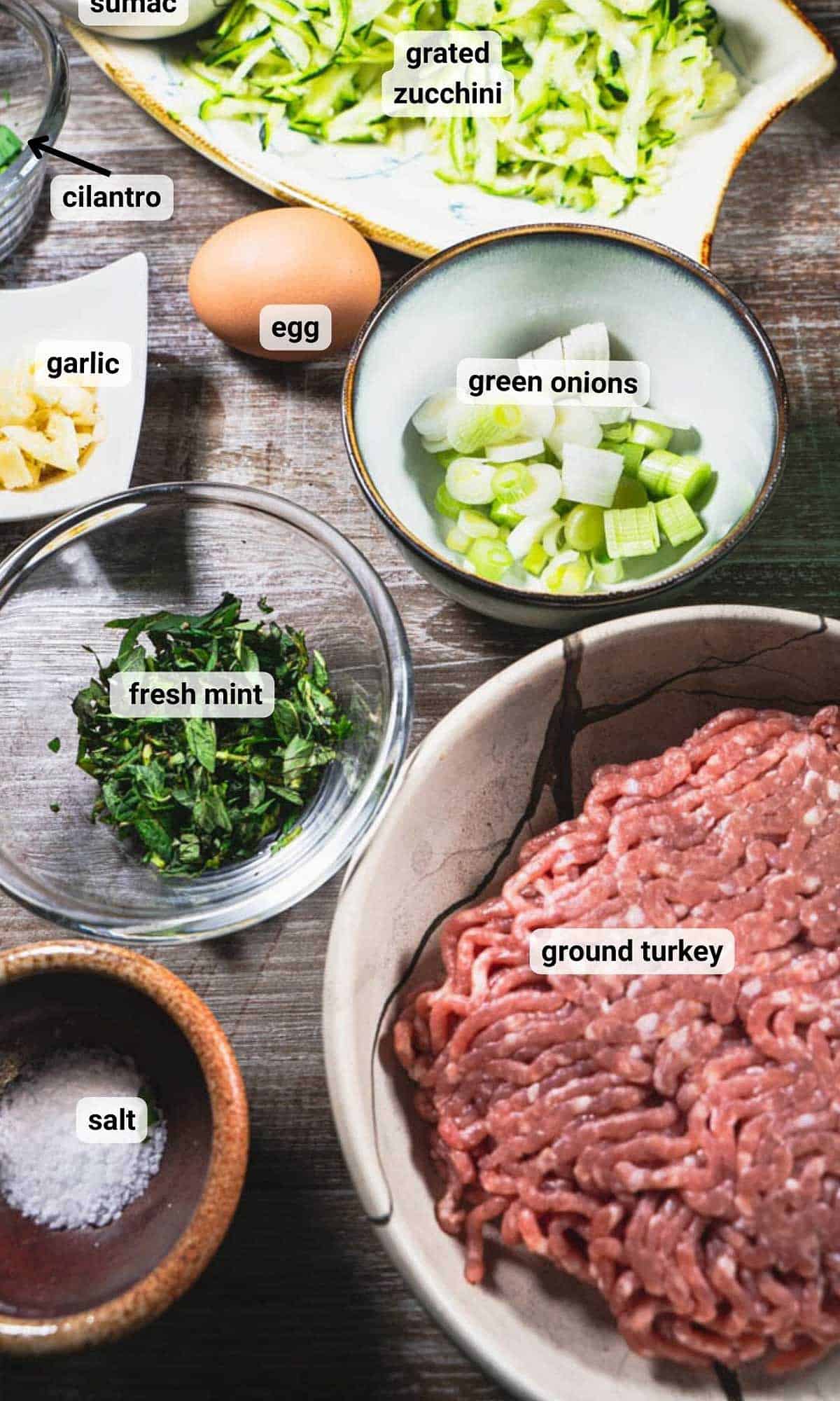 individual ingredients for turkey zucchini meatballs on a wooden table