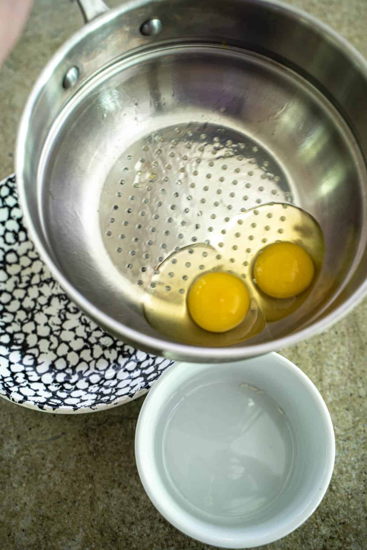 cracked eggs in a colander set over a bowl