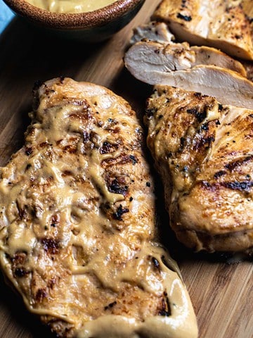 grilled mayo marinated chicken breasts on wooden cutting board