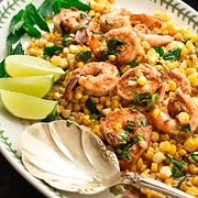 shrimp and corn tossed in lime dressing with lime slices on a serving platter