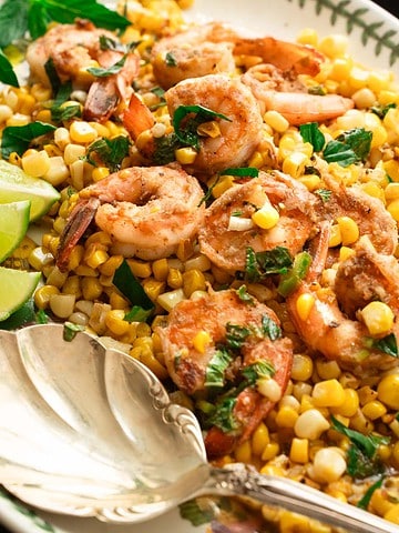 shrimp and corn tossed in lime dressing with lime slices on a serving platter