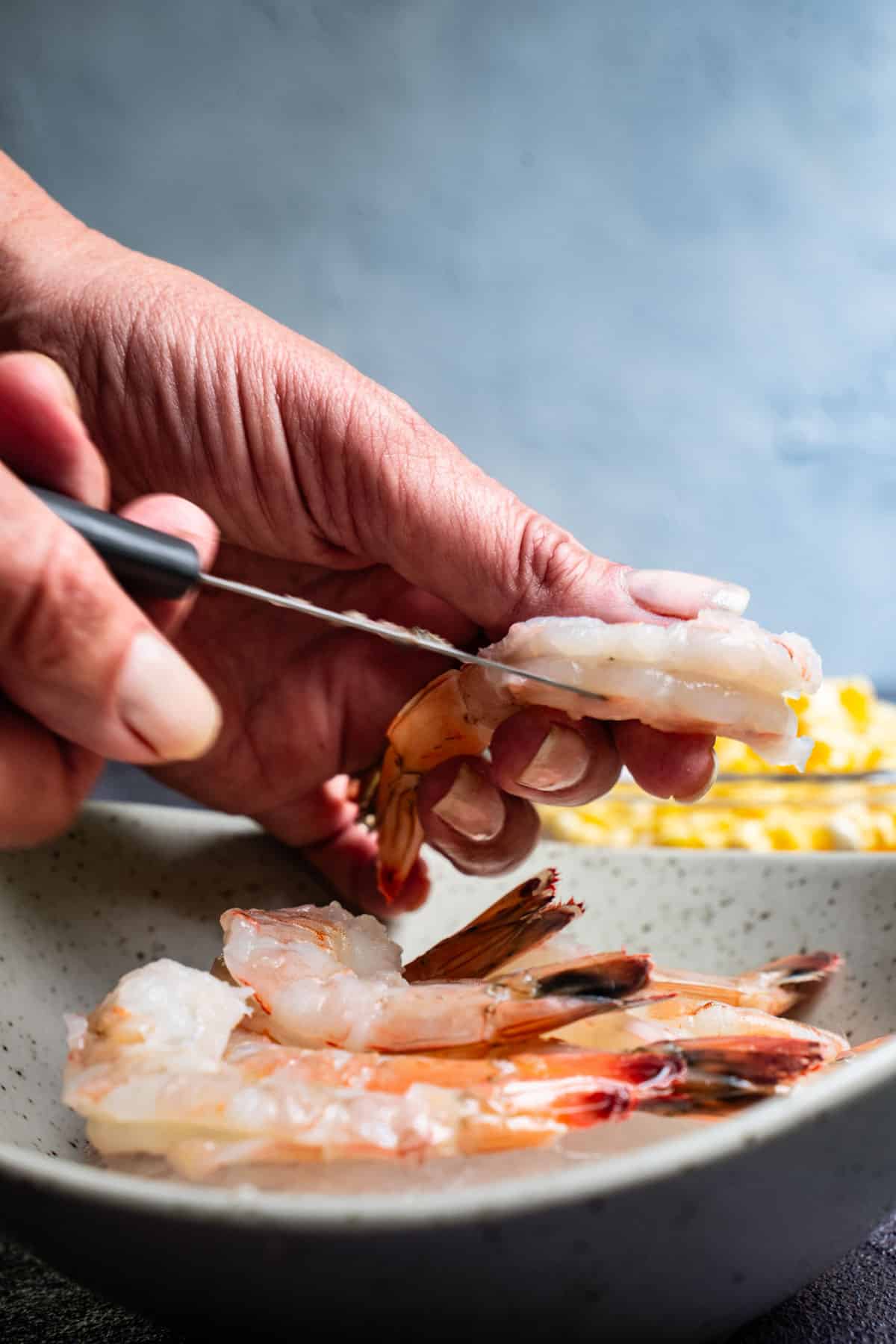 pairing knife making a shallow cut along the back of the shrimp exposing the vein.