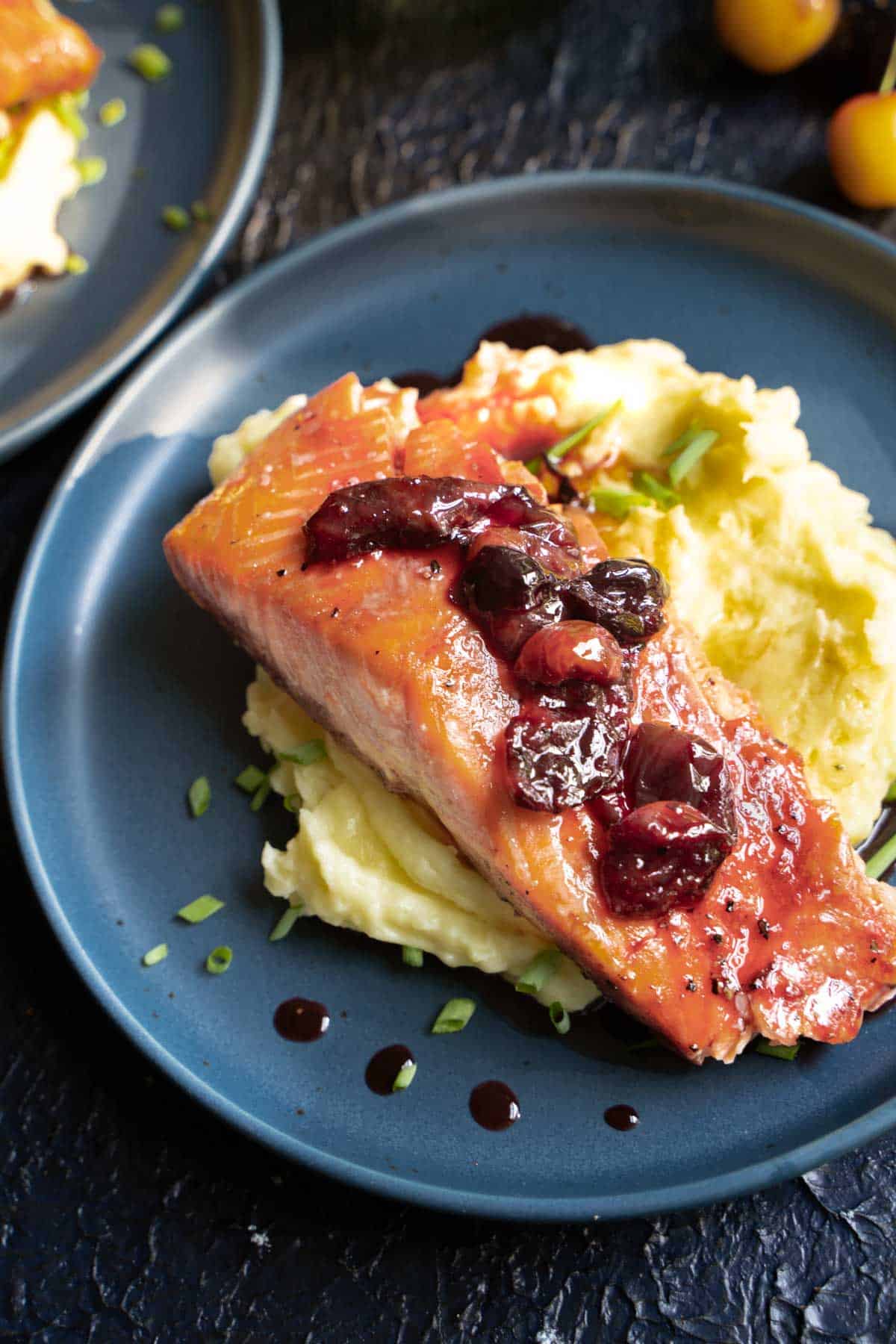Baked salmon with cherry glaze on a blue plate served over mashed potatoes