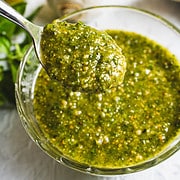 classic basil pesto on a spoon over a glass bowl