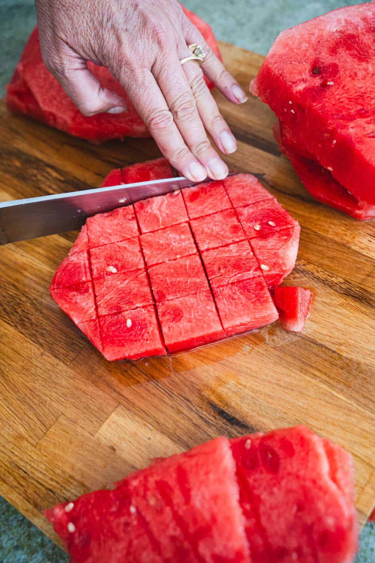 Cutting melon slabs into chunks on cutting board