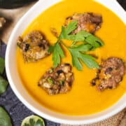 Creant Autumn Squash and Meatball Soup in a white soup bowl garnished with parsley.