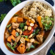 Thai red curry chicken and coconut rice in a white ramekin on burlap placed on a blue table