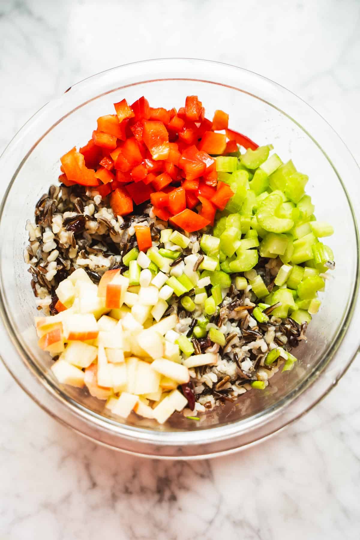 cold wild rice salad ingredients in a clear bowl