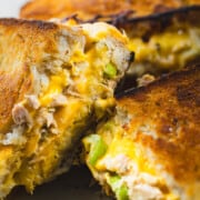 Sliced in half tuna cheese melt on parchment paper.